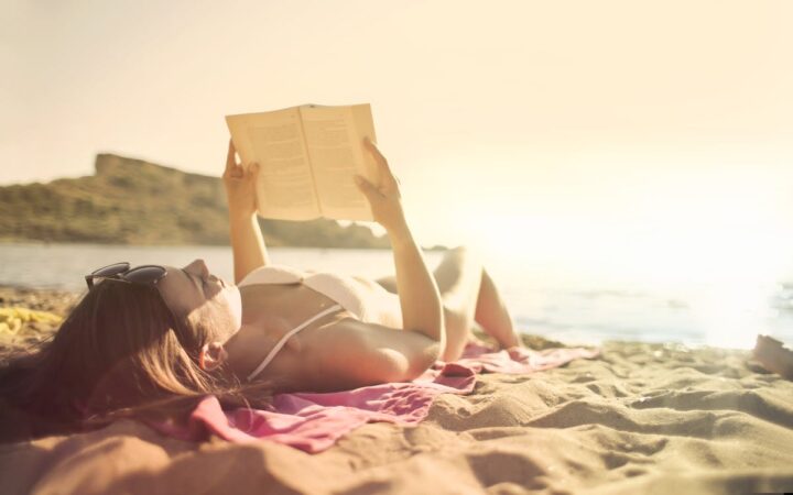 https://www.pexels.com/photo/woman-lying-on-beach-reading-book-3812741/