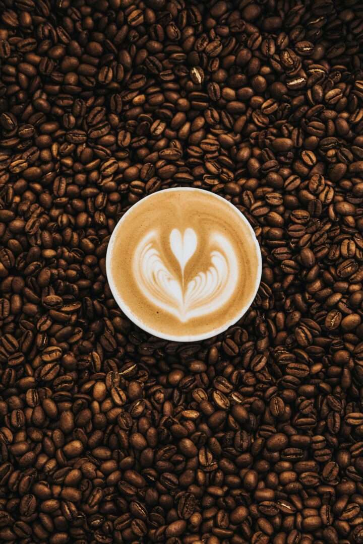 A cup of coffee surrounded by coffee beans