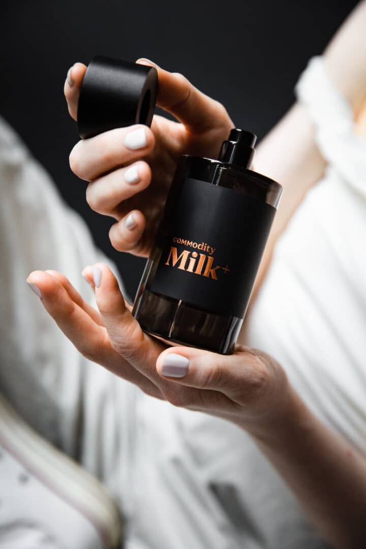 Commodity Milk Bold – schwarzer Flakon mit bronzefarbener Schrift in einer Hand gehalten