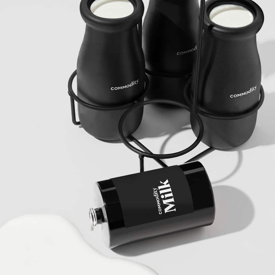 Commodity Milk Parfum – schwarzer Flakon im Bold-Design, inszeniert mit Milchflaschen