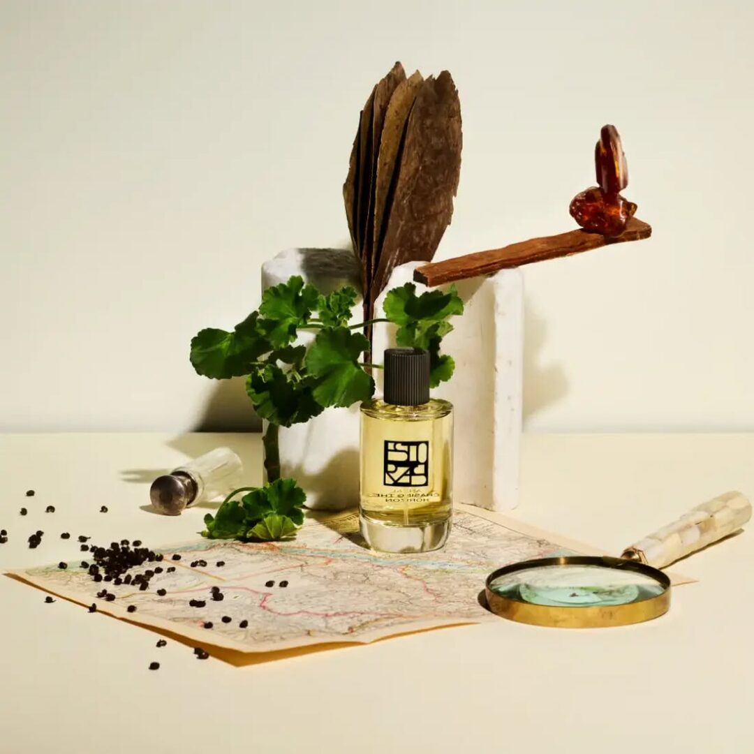 Antal von Estora's perfume bottle, staged on an old map with a magnifying glass, plants and expedition objects - a symbol of adventure and the spirit of discovery