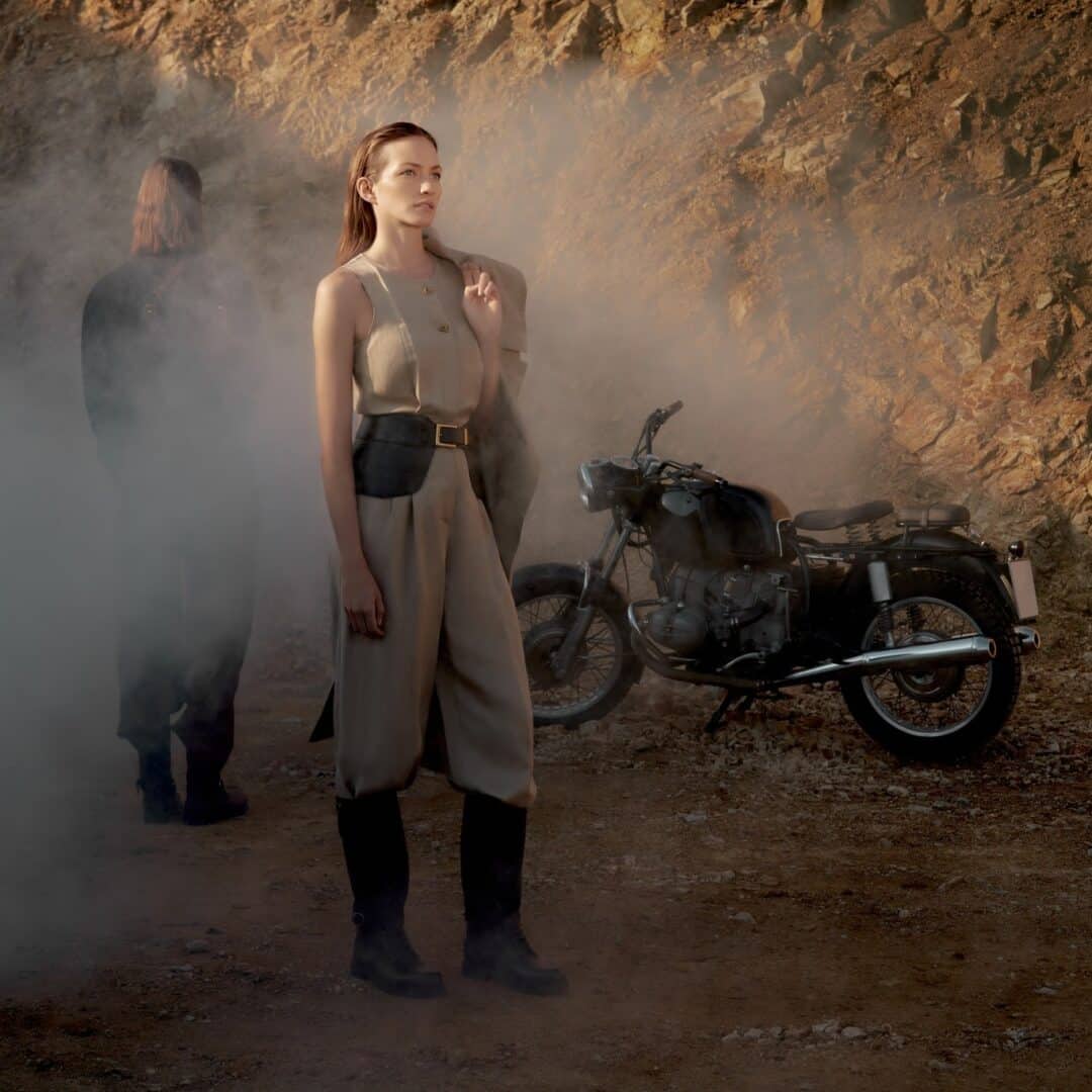 Estora's campaign motif - woman in safari look with motorcycle in desert-like landscape, inspired by The Adventures of Antal