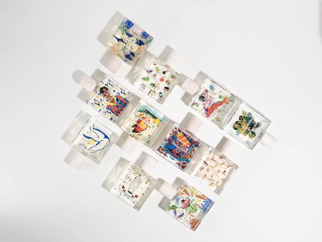 Mehrere rechteckige Parfumflakons von Maison Matine sind diagonal auf einem weißen Untergrund angeordnet. Jeder Flakon trägt eine individuelle, bunte Illustration – von grafischen Mustern über florale und figurative Motive bis hin zu humorvollen Zeichnungen. Die Vielfalt der Designs unterstreicht den kreativen, verspielten Charakter der Marke.