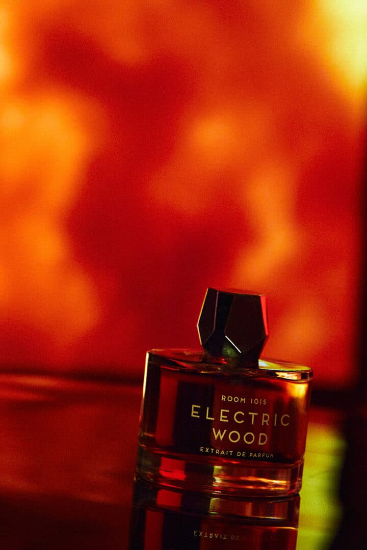 Flakon von Room 1015 Electric Wood Extrait de Parfum vor glühend rotem Hintergrund, symbolisch für Hitze, Energie und den rockigen Charakter des Dufts.
