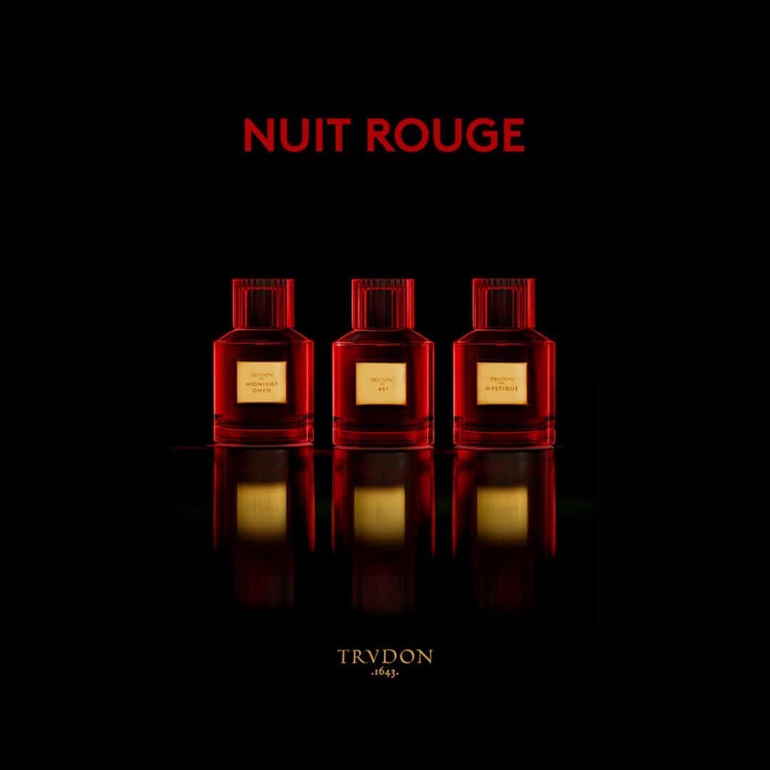 Red perfume bottles from the Nuit Rouge Collection by Trudon: Mystique, 45° and Midnight Omen. Three elegant bottles in deep red with golden labels against a black background.