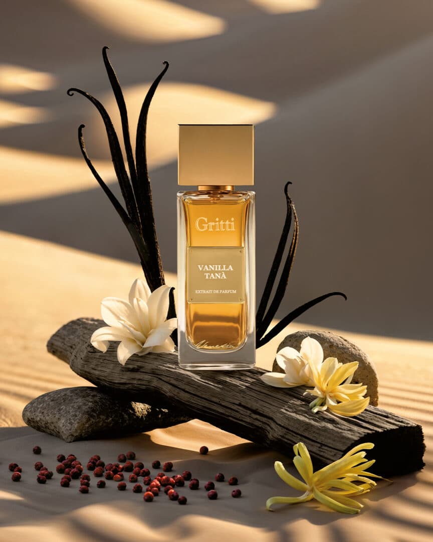 Gritti Vanilla Tanà – Flakon des Extrait de Parfum mit Vanilleschoten und Blüten auf sandfarbenem Hintergrund