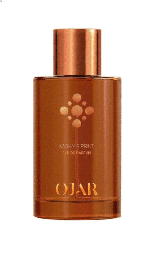 Flacon of the eau de parfum Kashmir Print by Ojar in an amber-colored glass bottle with a copper-colored cap against a white background.