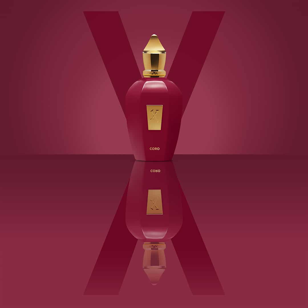 Xerjoff Coro Flakon in kräftigem Lachsrot mit goldener Kappe vor monochromem Hintergrund und gespiegelt im Untergrund.