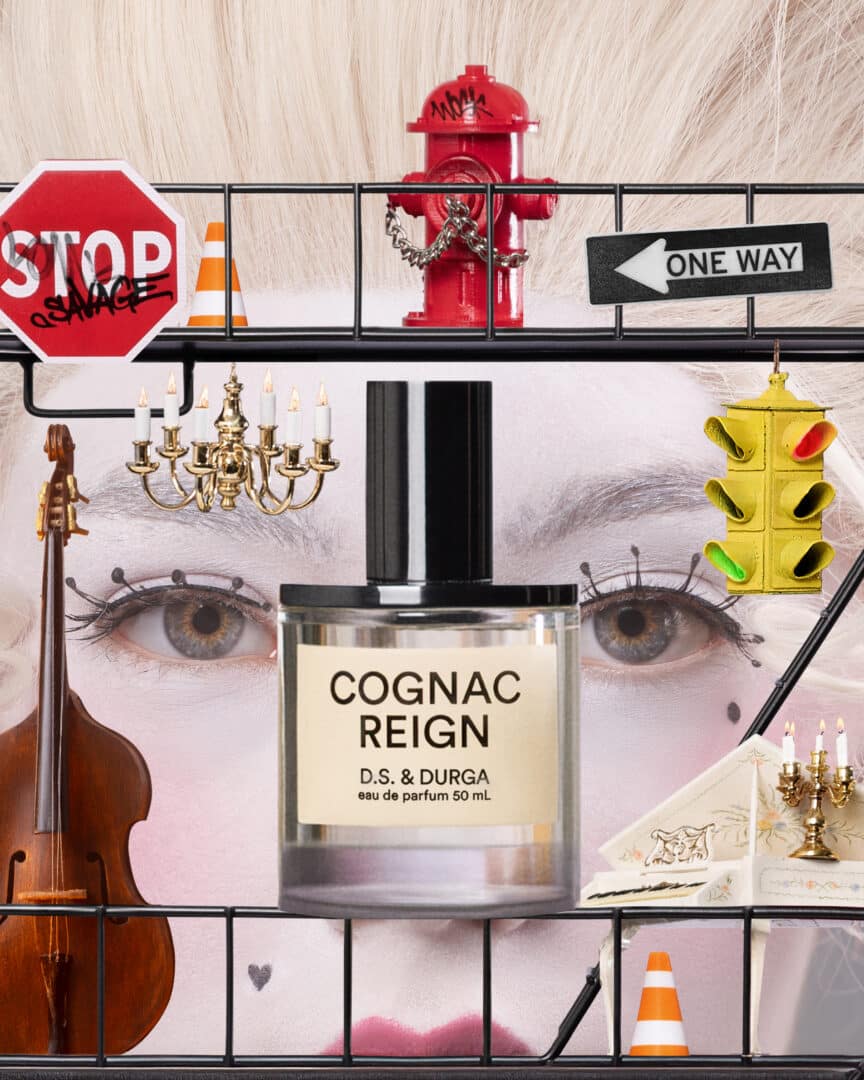 Flacon of Cognac Reign by D.S. &amp; Durga in front of a collage of baroque and metropolitan elements with a white powdered wig, red hydrant, chandeliers and traffic signs - a visual fusion of Versailles and New York.