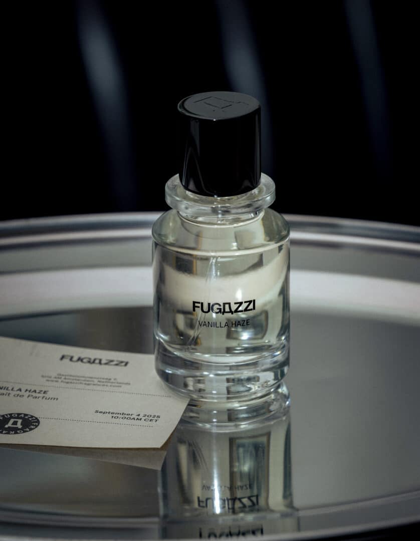 Flakon von Vanilla Haze Extrait von Fugazzi auf einem silbernen Tablett mit Spiegelung und Karte im Vordergrund. Moderner, minimalistischer Glasflakon mit schwarzem Verschluss.