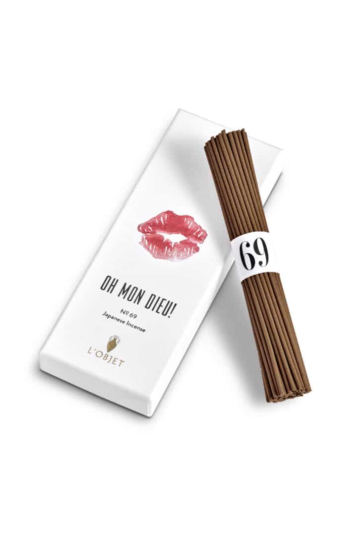L’Objet Oh Mon Dieu! Nº 69 Japanese Incense mit weißer Verpackung und rotem Kussabdruck, daneben ein Bündel brauner Räucherstäbchen.