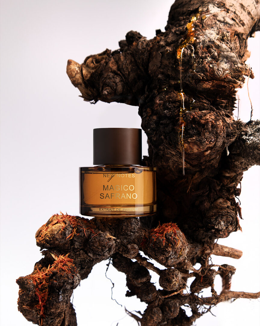 New Notes Magico Safrano Extrait de Parfum – honigfarbener Flakon vor strukturierter Baumwurzel mit Safranfäden und Harzdetails