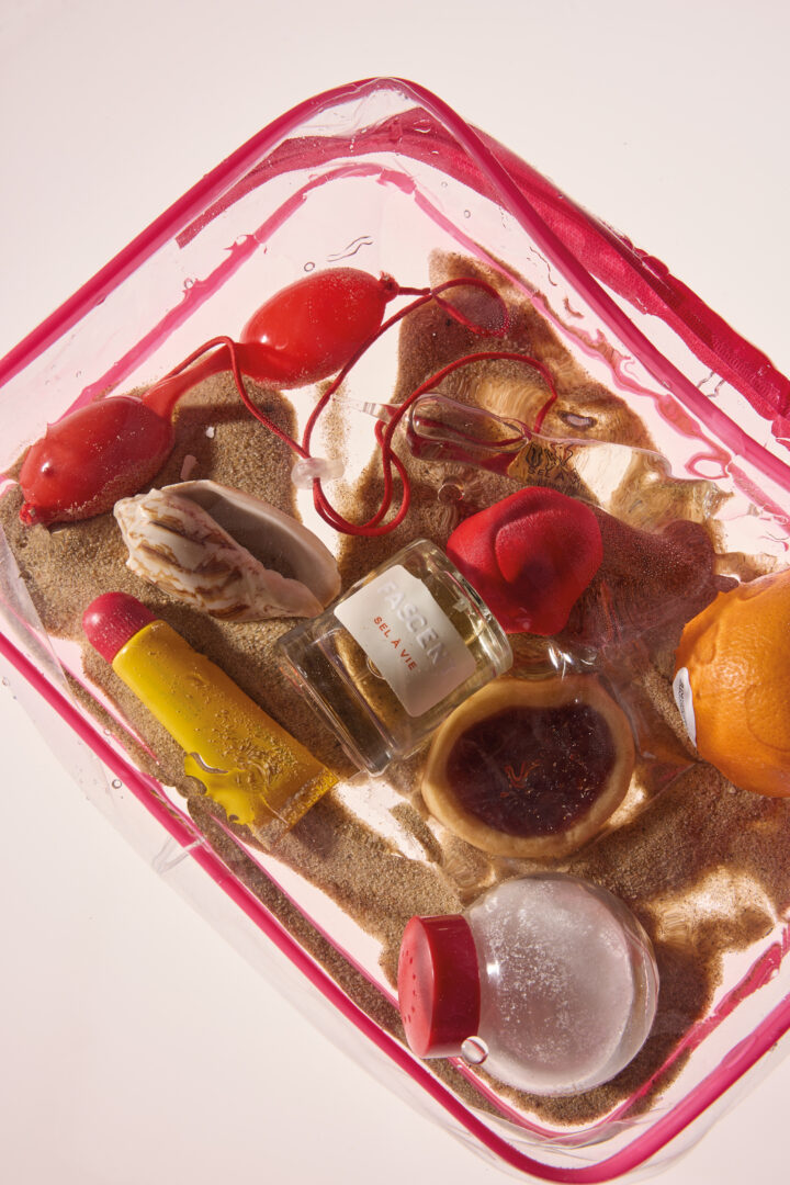 Fascent Sel à Vie Eau de Parfum – Parfumflakon der Marke Fascent in farbigem Stillleben mit Sand, Glasobjekten und roten Akzenten