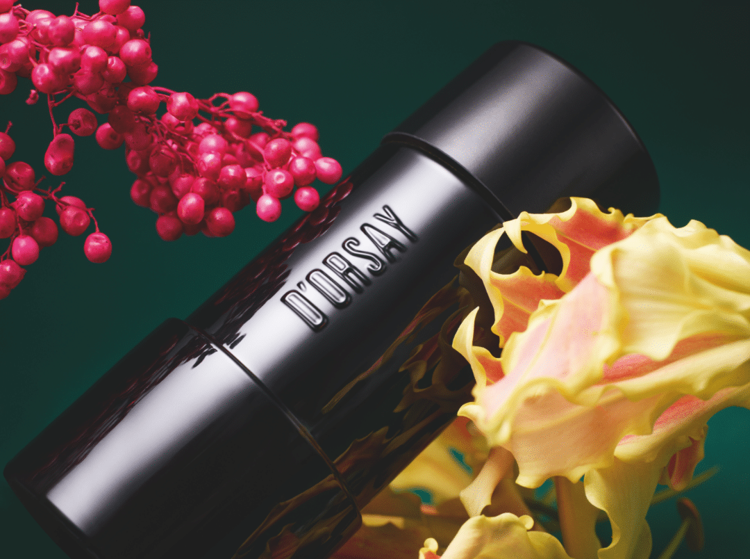 Flakon von Flower Lust von D’Orsay Extrait de Parfum, inszeniert mit gelben Blüten und roten Beeren vor dunklem Hintergrund