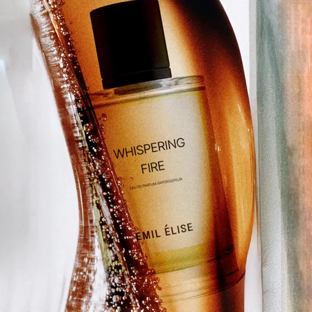 Whispering Fire von Emil Élise – warmer, ambrierter Duft im eleganten Glasflakon Whispering Fire von Emil Élise in goldenem Glasflakon, inszeniert mit warmen, fließenden Texturen und lichtdurchlässigen Amber-Tönen