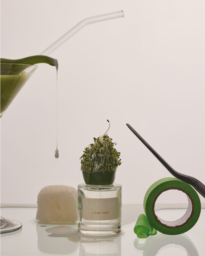 Fascent I Fig You Eau de Parfum – Parfumflakon der Marke Fascent in grünem Stillleben mit Feige, Glasgefäß und floralen Akzenten