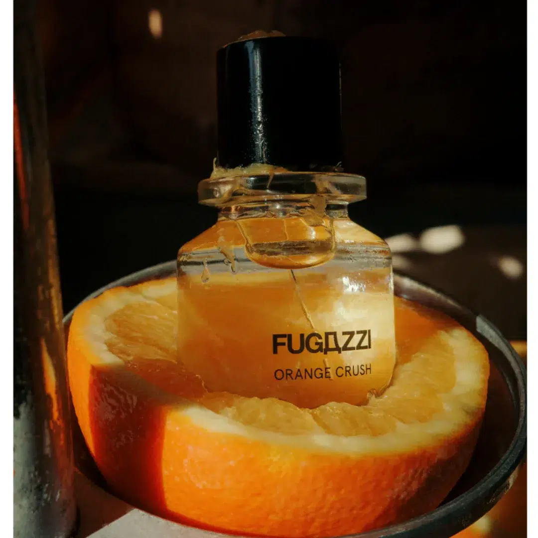 Fugazzi Orange Crush – spritziger Orangenakkord Fugazzi Orange Crush Flakon in einer halbierten Orange platziert – leuchtend-zitrische Duftinszenierung.