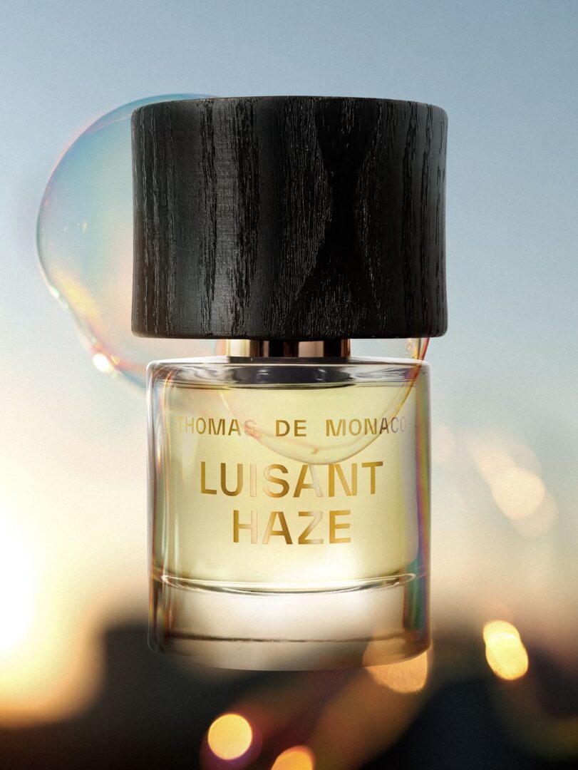 Flakon von Luisant Haze von Thomas De Monaco vor einem lichtdurchfluteten Hintergrund mit schimmernder Seifenblase und goldenen Reflexen.