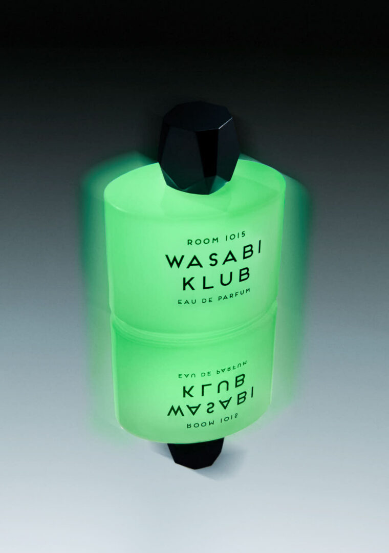 Room 1015 Wasabi Klub Eau de Parfum mit grün leuchtendem Glow-in-the-Dark-Flakon auf spiegelnder Oberfläche.