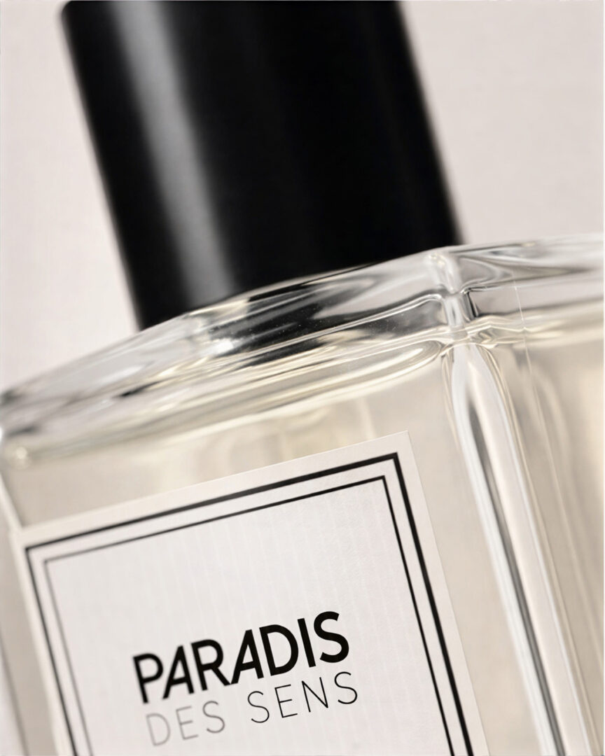 Close-up of a bottle from the niche fragrance brand Paradis des Sens, featuring a black cap and a white label.