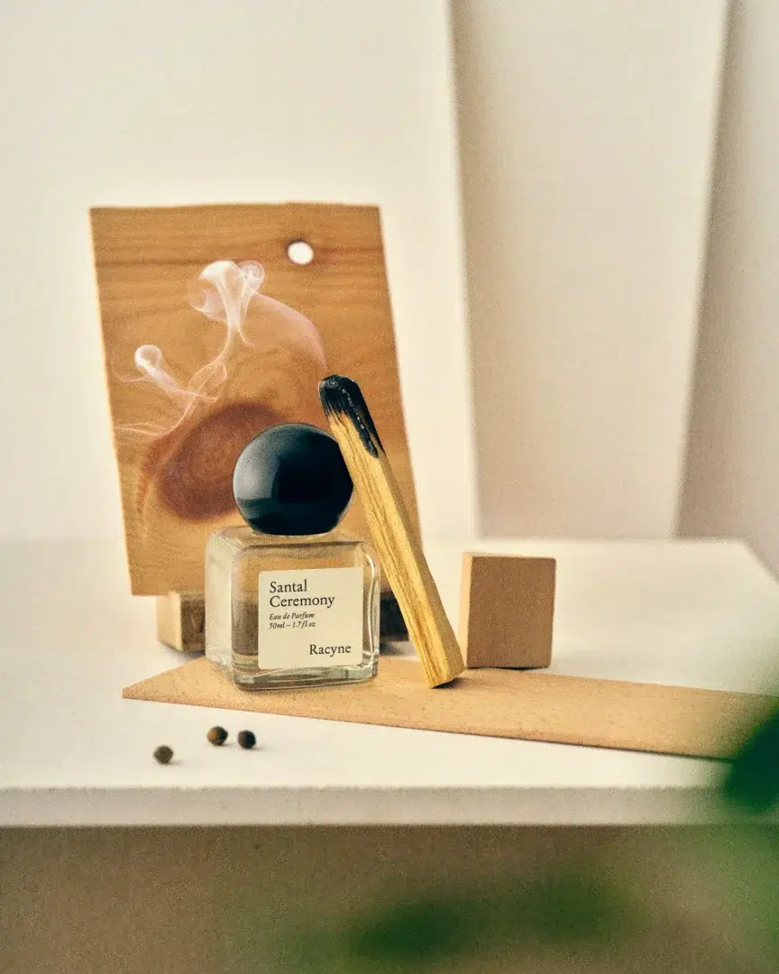 Racyne – Santal Ceremony Racyne Santal Ceremony mit schwarzem Verschluss, Holz und Gewürzen in einer warmen, minimalistischen Inszenierung